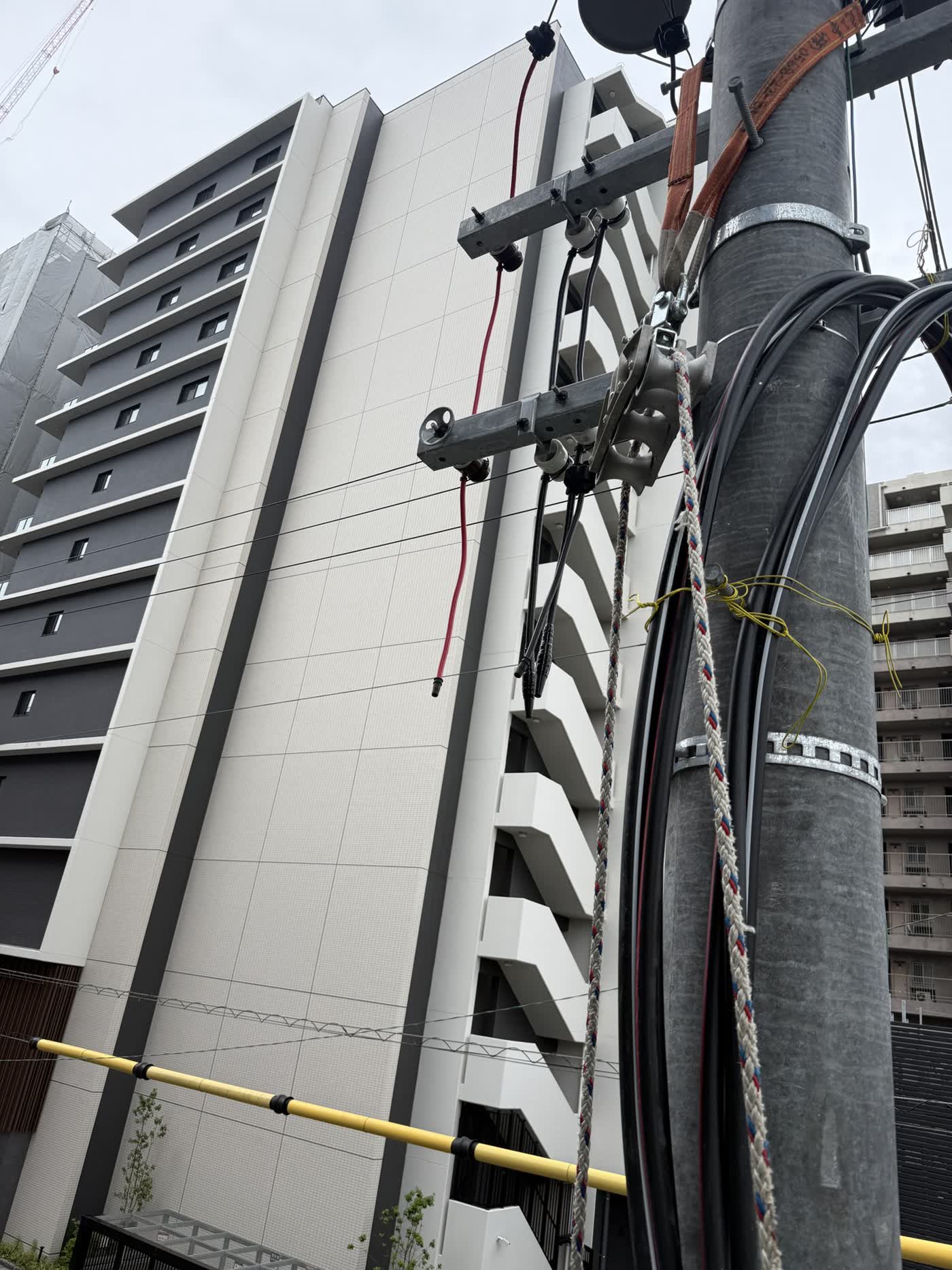 電柱にまとめられたケーブルと新築マンション